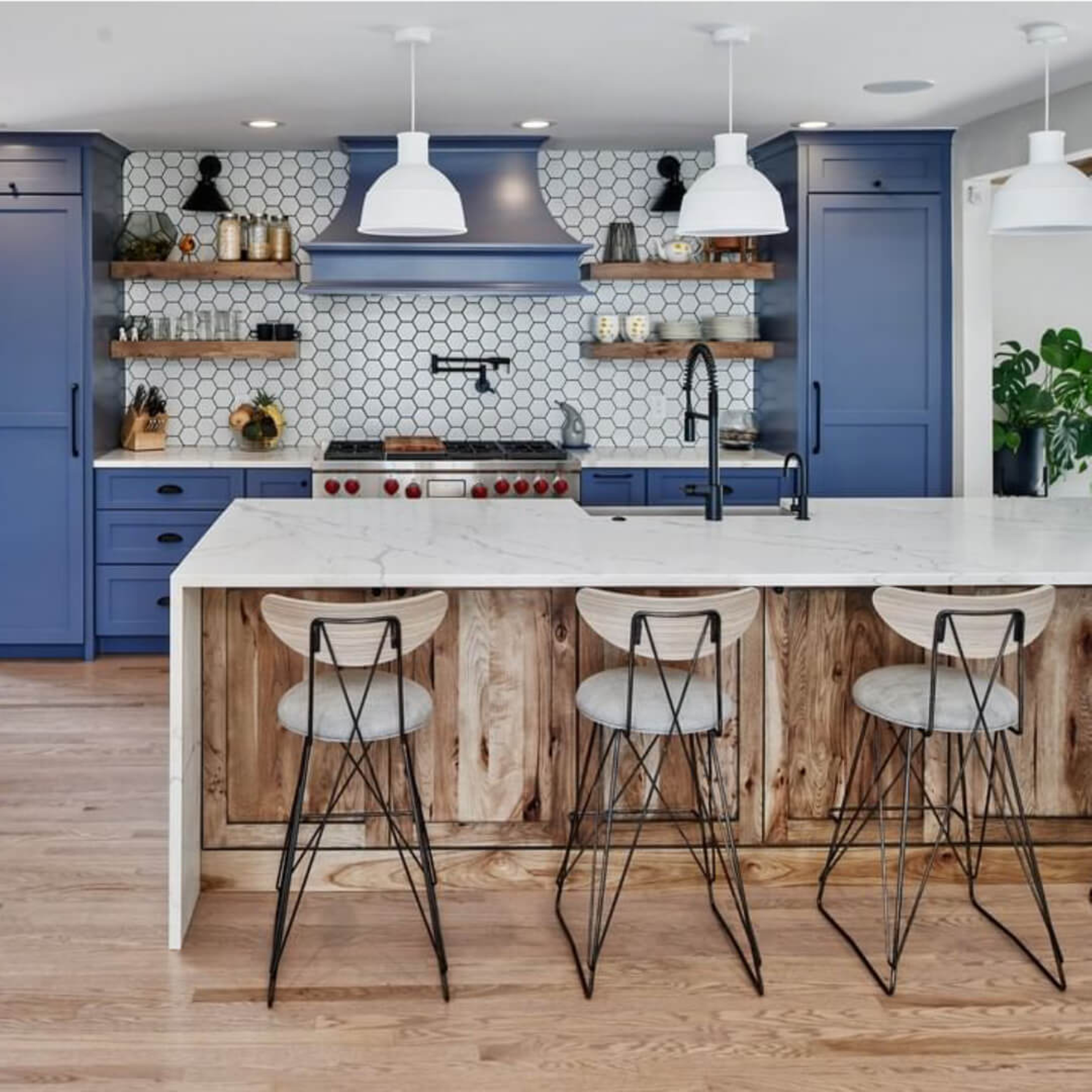 Modern kitchen looking over center island with blue cabinetry and a hexagonal patterned back splash.